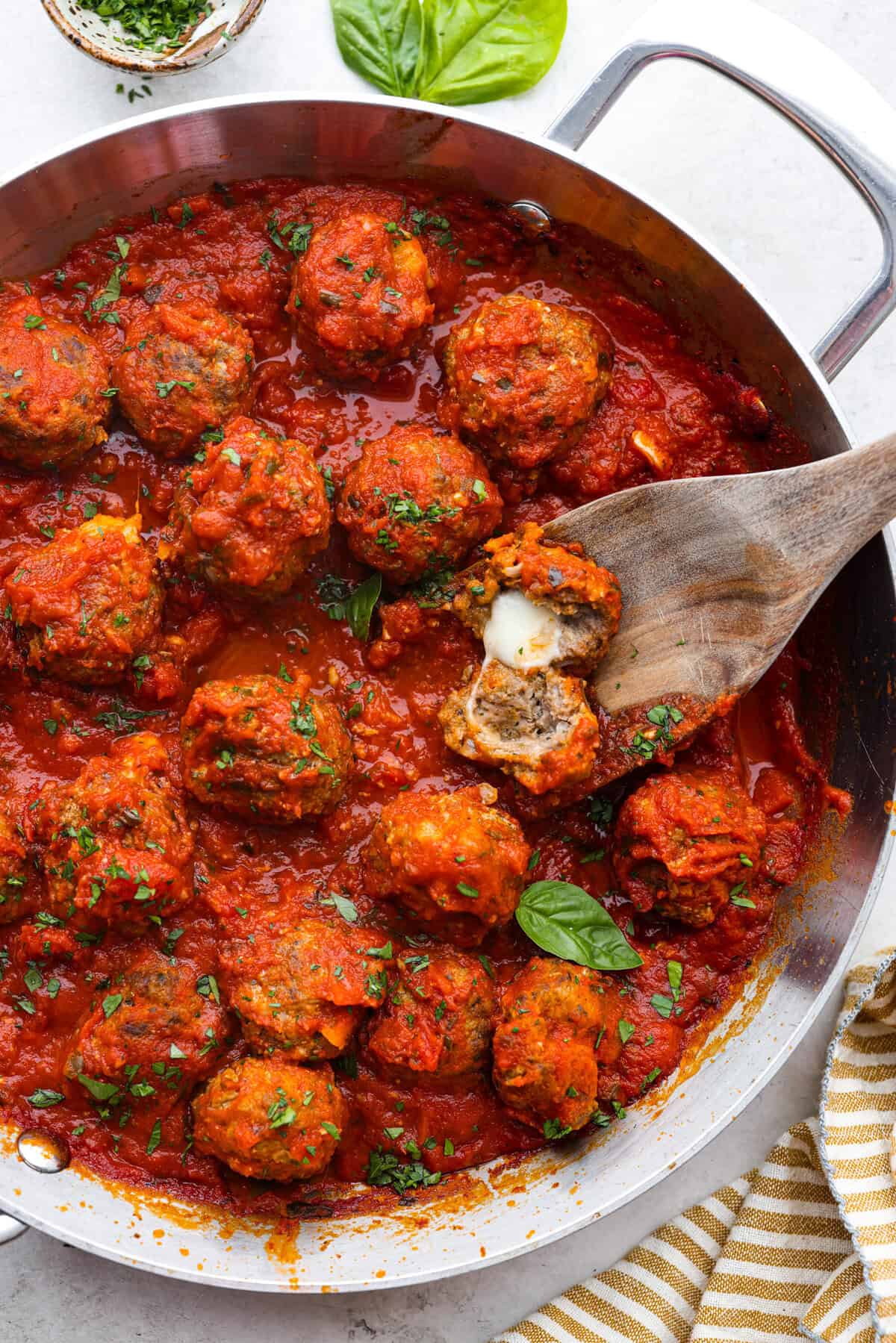Mozzarella Stuffed Meatballs take classic meatballs to the next level! Tender and juicy with melty cheese on the inside. Serve these meatballs as a party appetizer or over spaghetti noodles for a hearty meal! Top view of mozzarella stuffed meatballs in a skillet.