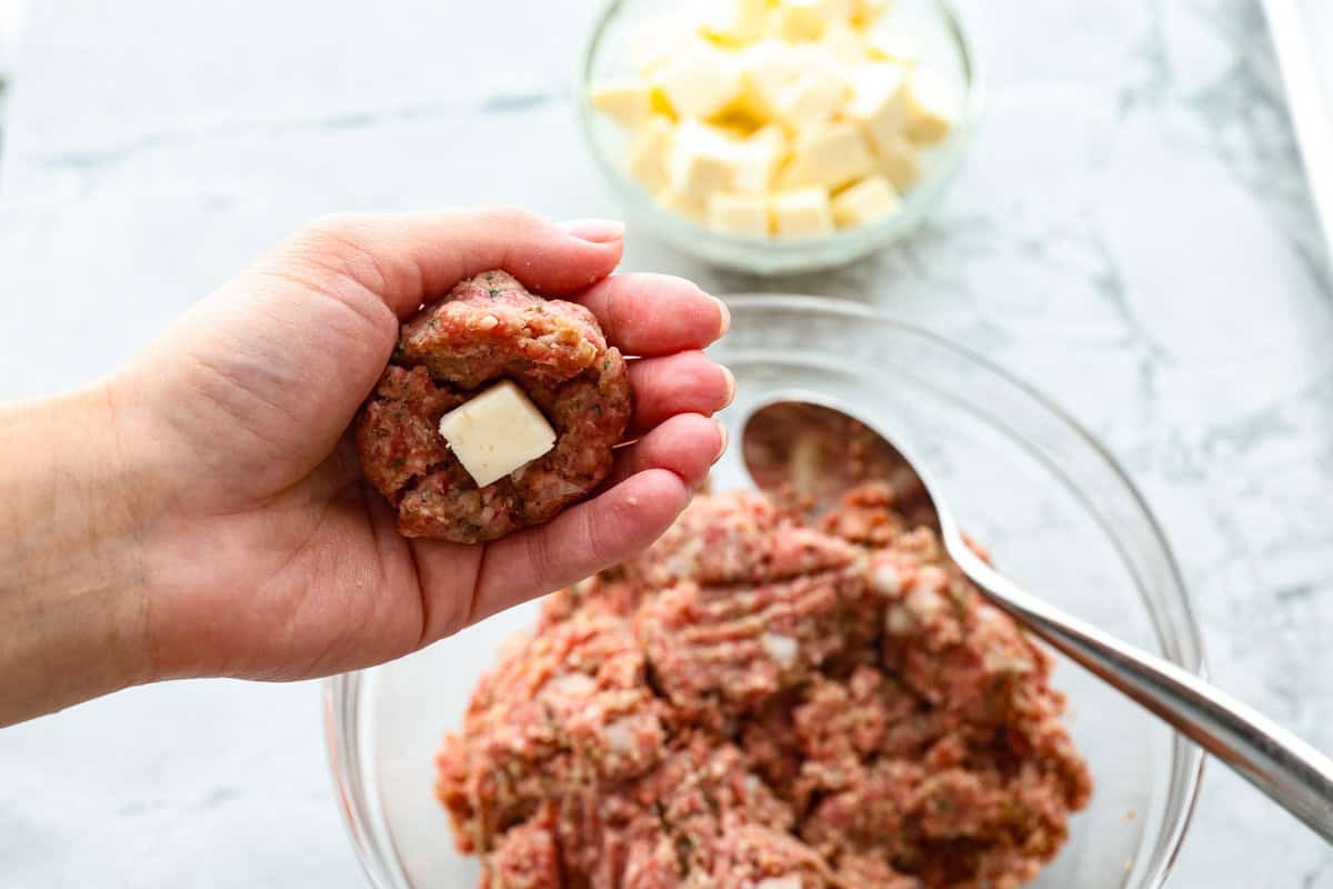 Mozzarella Stuffed Meatballs take classic meatballs to the next level! Tender and juicy with melty cheese on the inside. Serve these meatballs as a party appetizer or over spaghetti noodles for a hearty meal! Third photo of the cheese being stuffed in the meatball.