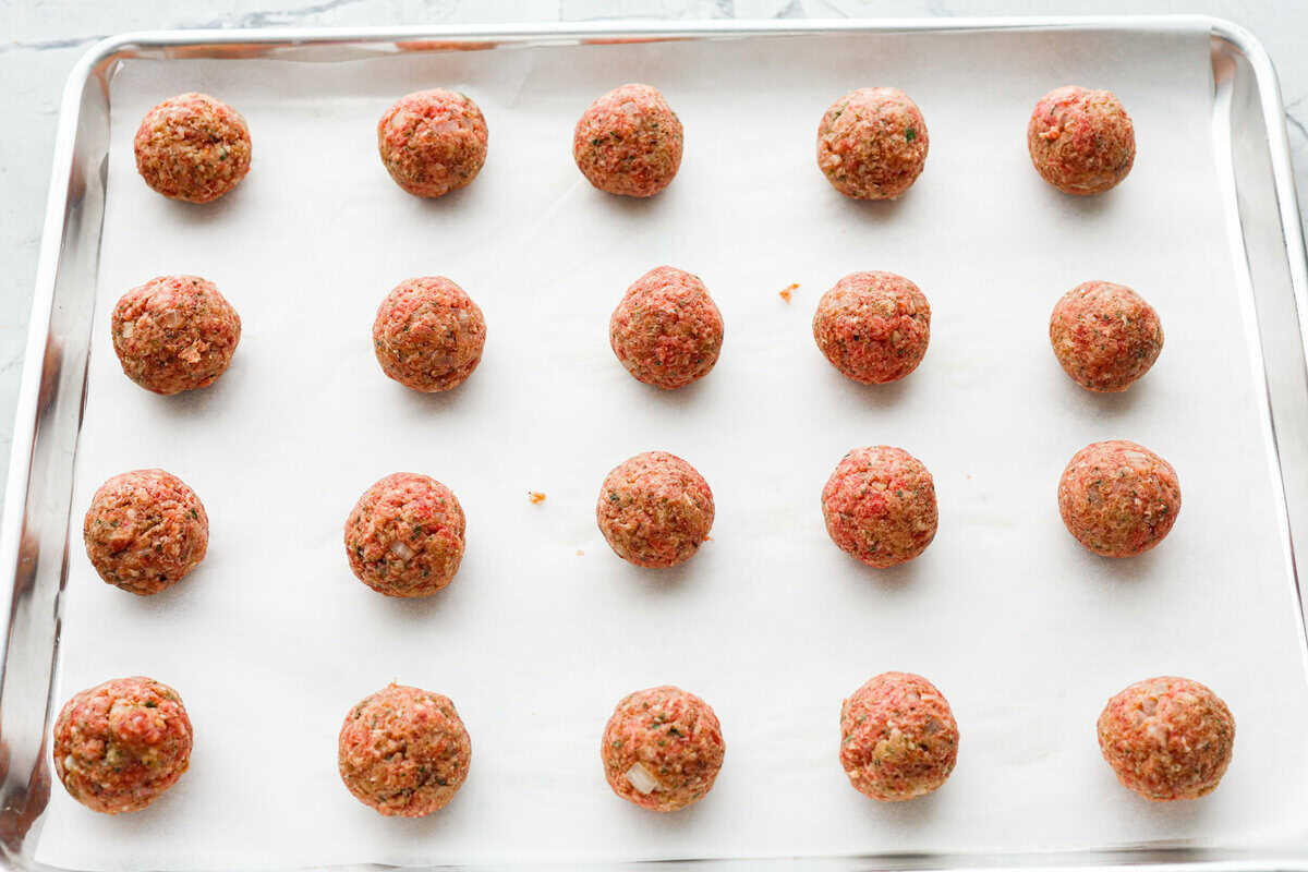 Mozzarella Stuffed Meatballs take classic meatballs to the next level! Tender and juicy with melty cheese on the inside. Serve these meatballs as a party appetizer or over spaghetti noodles for a hearty meal! Fourth photo of the mozzarella stuffed meatballs placed on a baking sheet to bake.