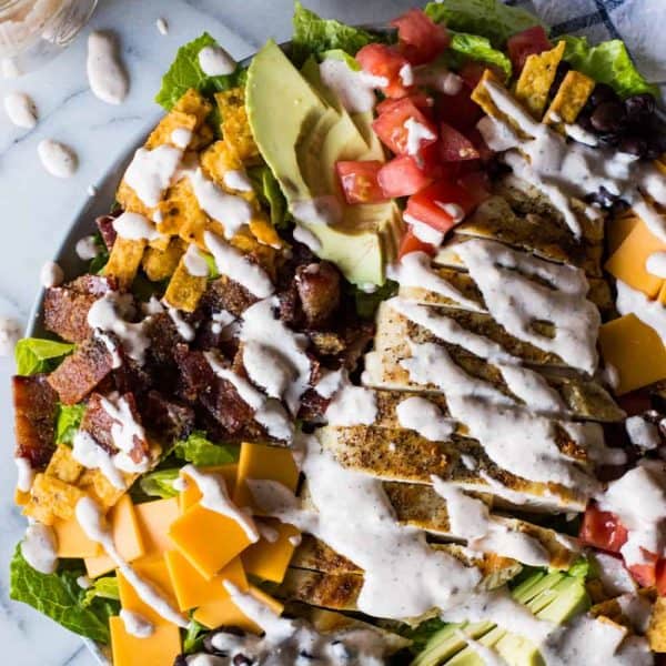 Southwest Grilled Chicken Salad with Candied Bacon. This salad is loaded with grilled chicken, fresh juicy tomato, creamy avocado, crunchy tortilla strips, black beans, cheddar cheese, and sweet and salty candied bacon. All drizzled with a homemade salsa ranch that is truly addicting!