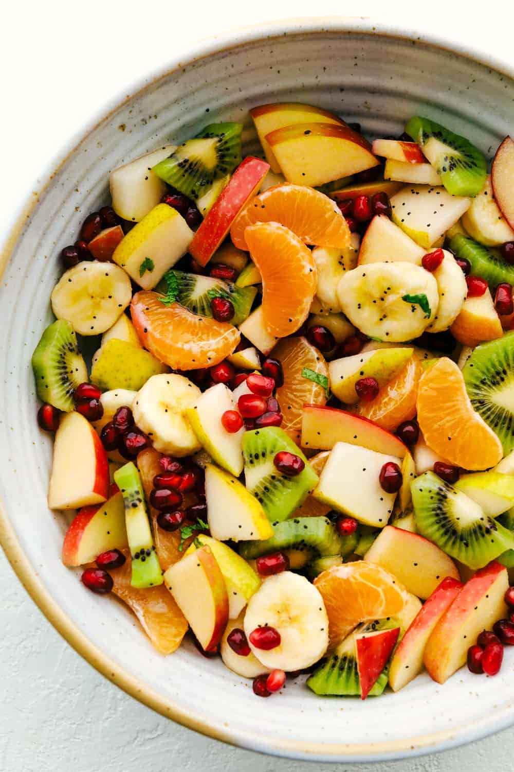 Ensalada de frutas de invierno con plátanos, manzanas, naranjas, kiwi y granadas. 