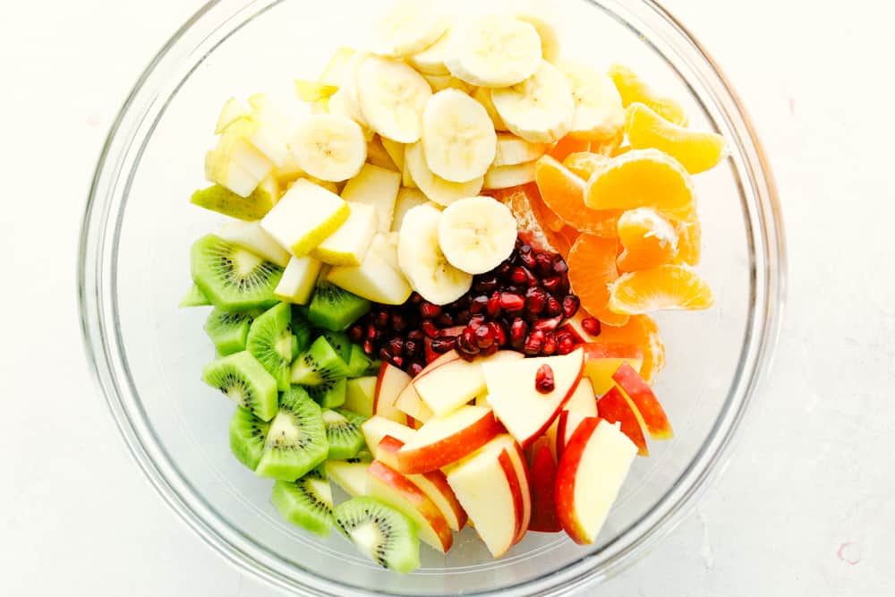 Ensalada de frutas de invierno con plátanos, manzanas, naranjas, kiwi y granadas. 