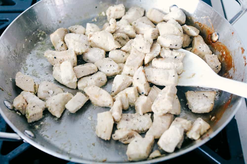 Stir frying the chicken in the wok. 