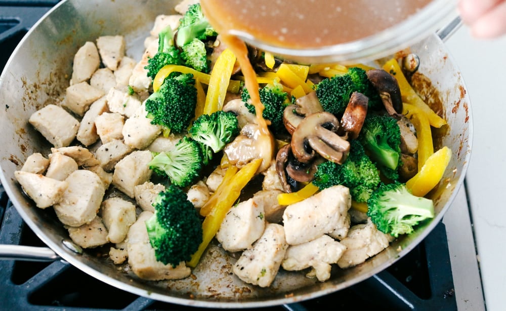 Adding the vegetables to the chicken and the sauce. 