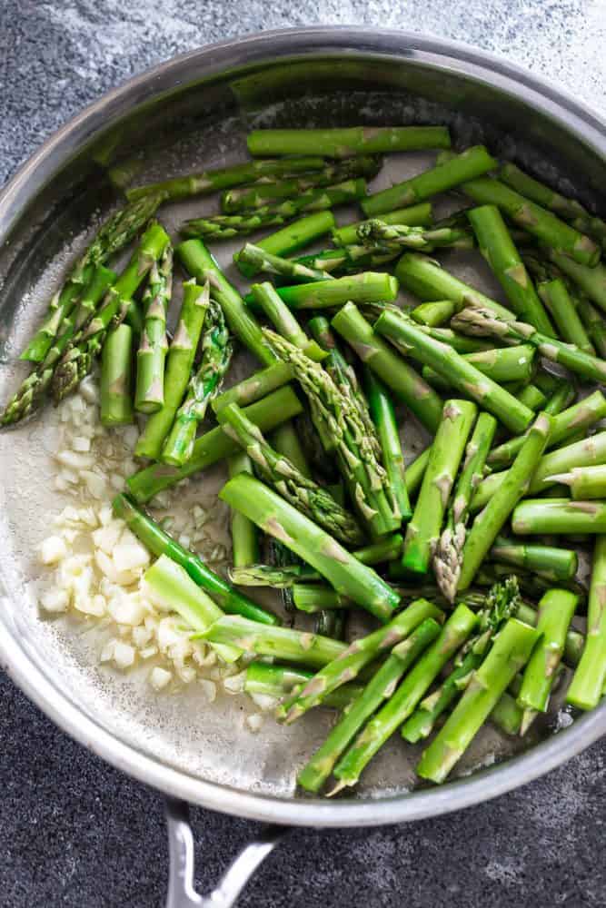 Asparagus cooking with onion in a saute pan.