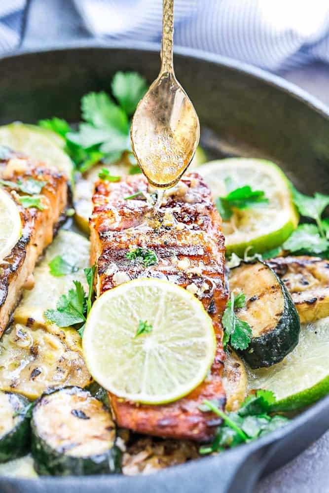 Honey being drizzled over Salmon fillets in a skillet