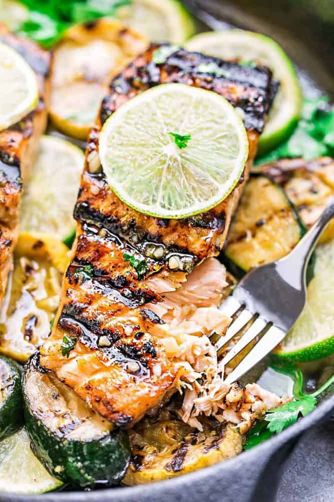 Close-up of Honey Lime Salmon fillet over sliced zucchini and limes