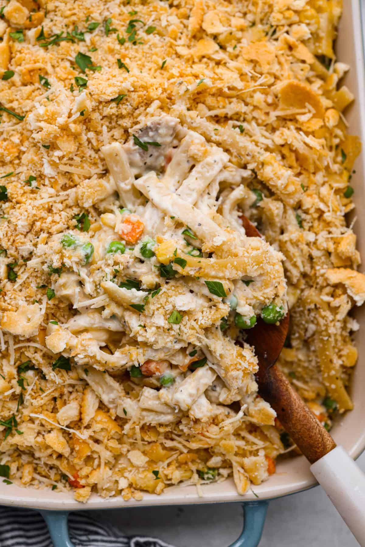 Close up shot of creamy chicken noodle casserole with wooden serving spoon. 