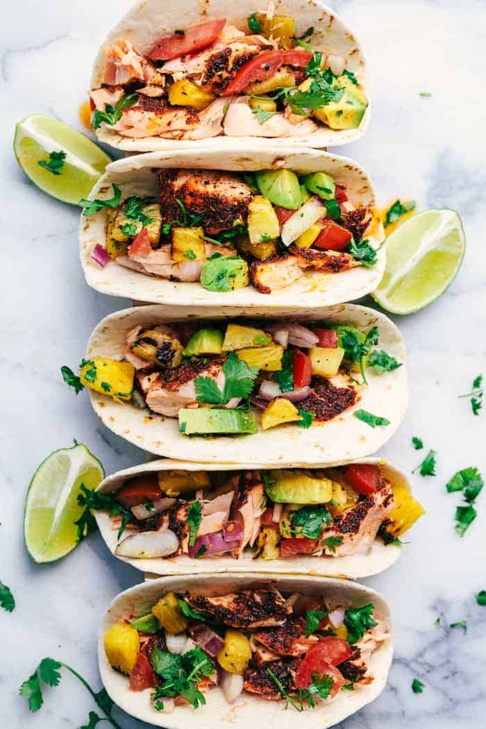 Grilled Spicy Blackened Salmon Tacos with Pineapple Avocado Salsa in a row.