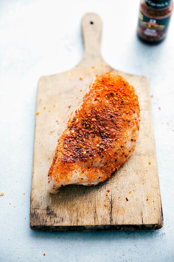 Seasoned chicken on a wooden plank.