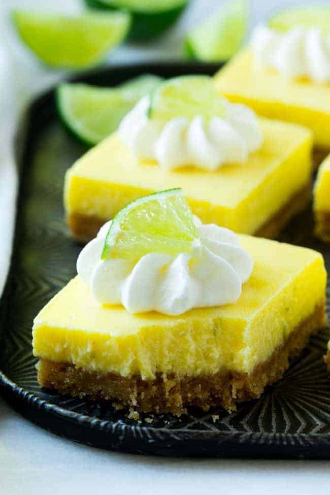 Bite out of key lime pie bar on a black plate. 
