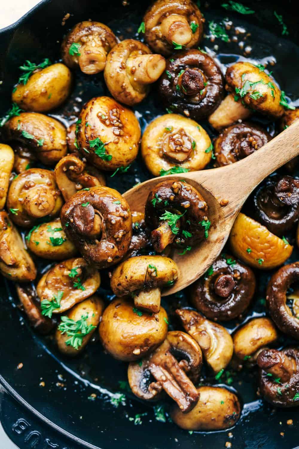 Honey Balsamic Garlic Mushrooms being scooped into a wooden spoon.