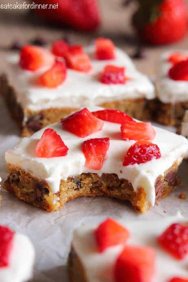 Chocolate Chip Cookie Cheesecake Bars with Strawberries with a bite taken out.