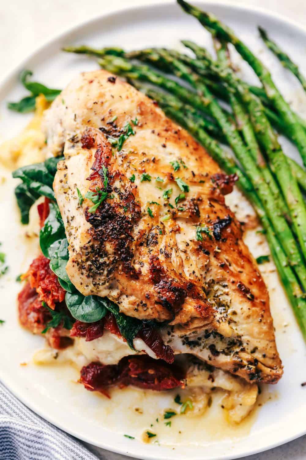 Stuffed Tuscan Garlic Chicken on a white plate with asparagus.