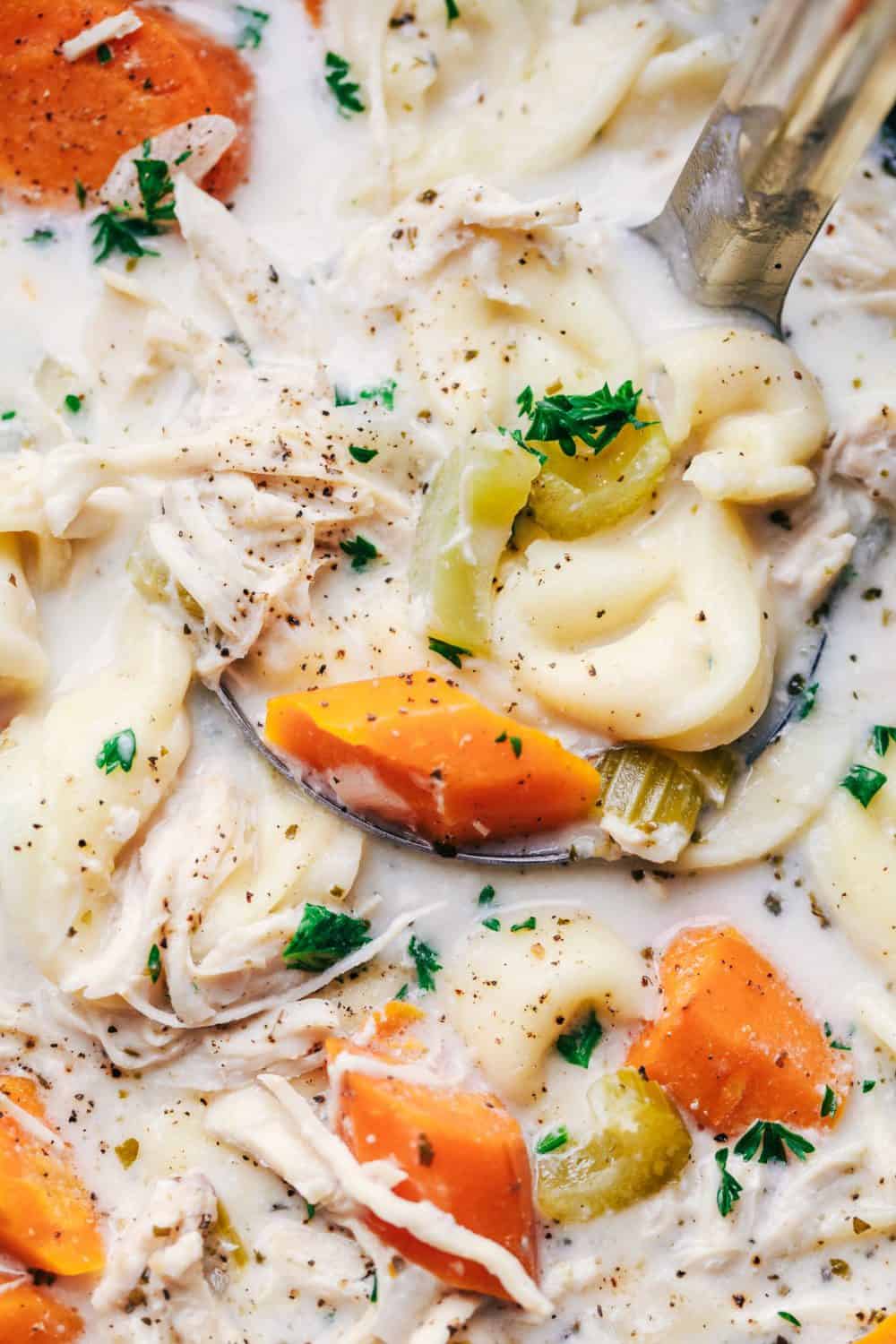 Slow Cooker Creamy Chicken Tortellini Soup being scooped up by a spoon.