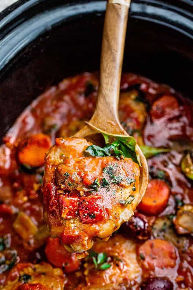 Scooping up slow Cooker Chicken Cacciatore with a wooden spoon.