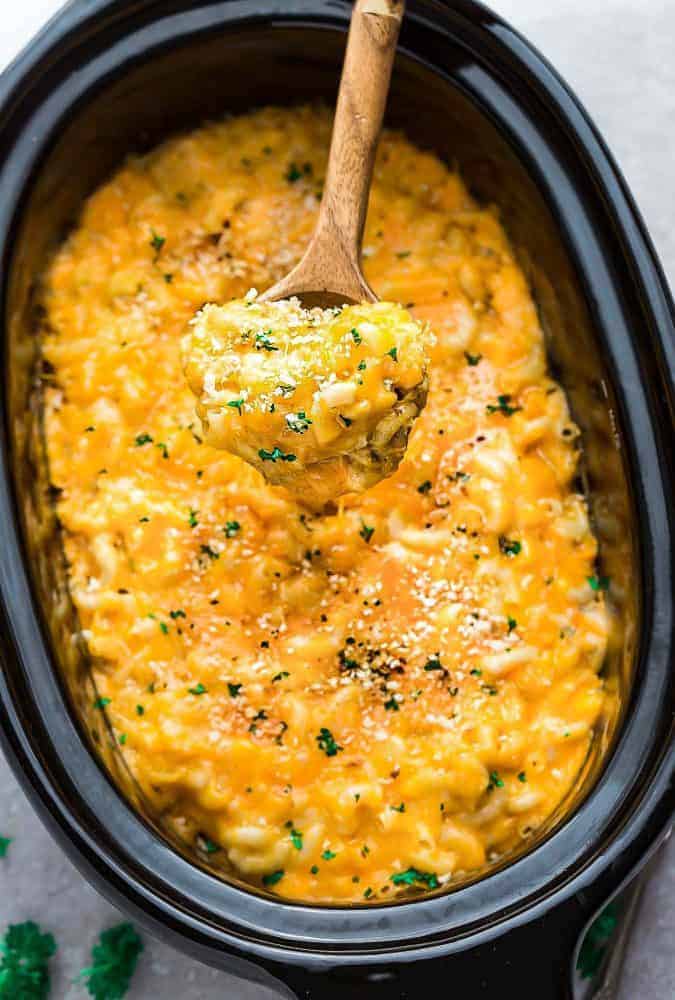 Slow Cooker Macaroni and Cheese in a crock pot with a spoonful in a wooden spoon.