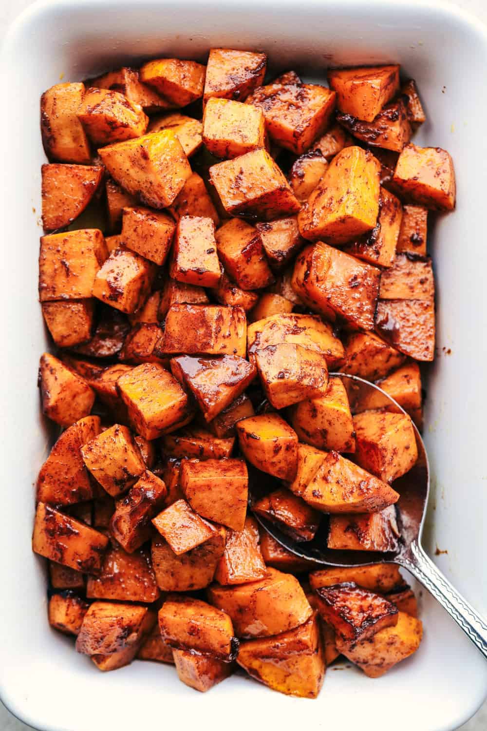Roasted Honey Cinnamon Butter Sweet Potatoes in a white baking dish.