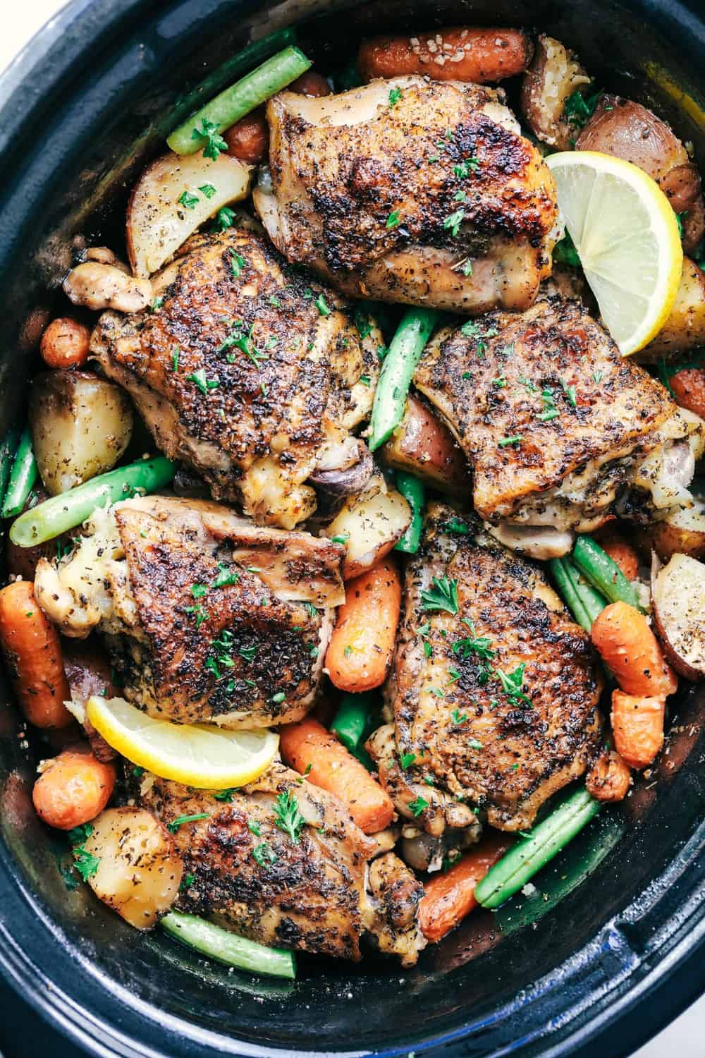 View from above of Slow Cooker Lemon Garlic Chicken Thighs and Veggies in a slow cooker.