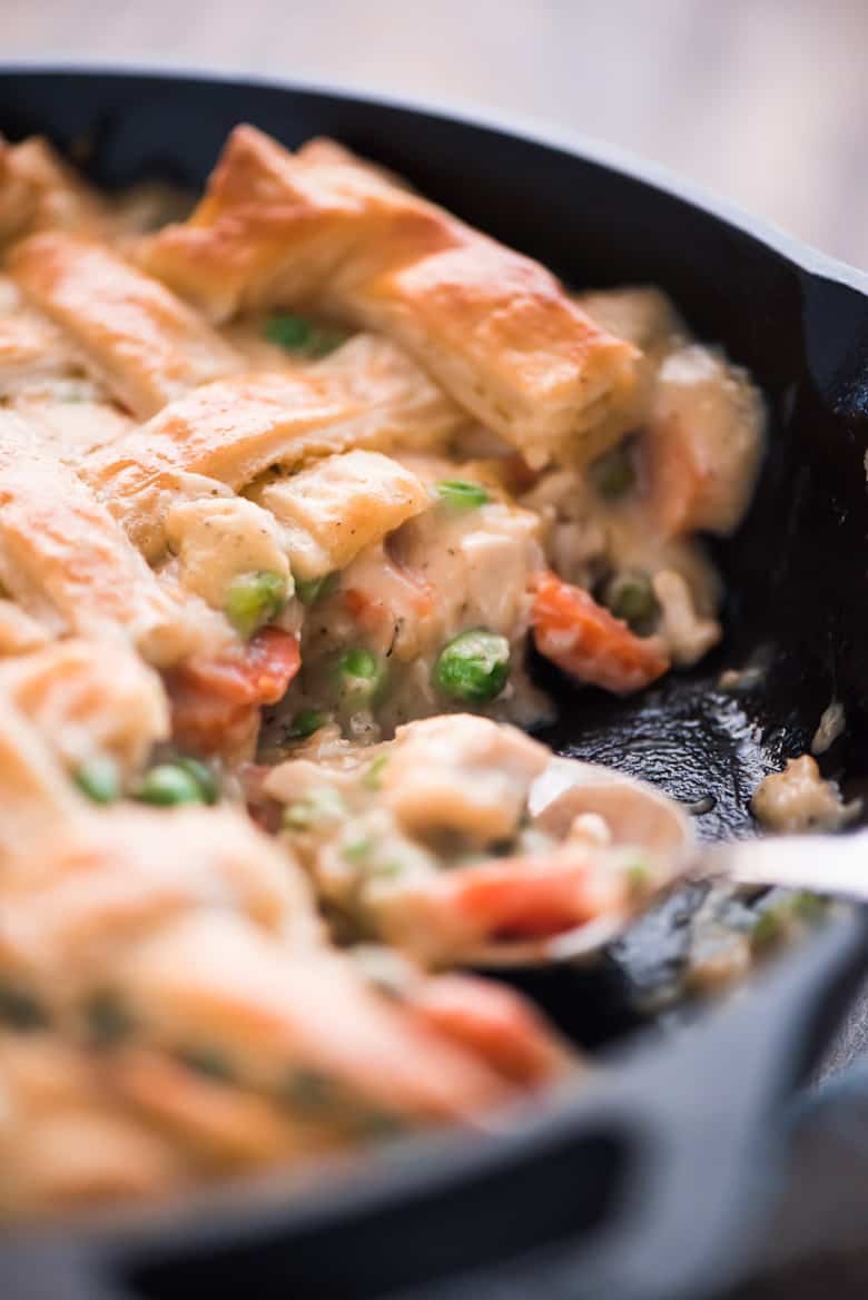 One Skillet Chicken Pot Pie being scooped out of a skillet with a spoon.