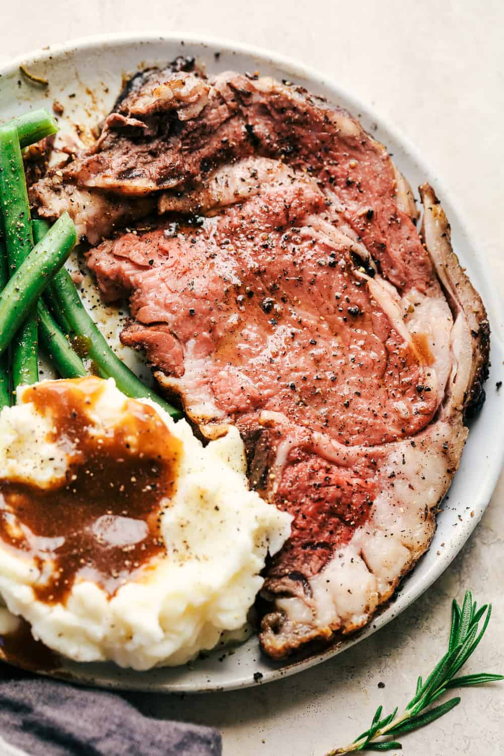 Prime rib with beans and potatoes on a plate. 