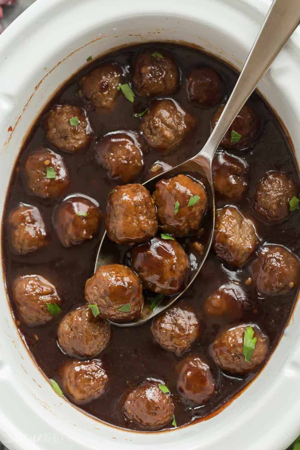 Slow Cooker Cranberry Balsamic Meatballs being scooped up by a big serving spoon.