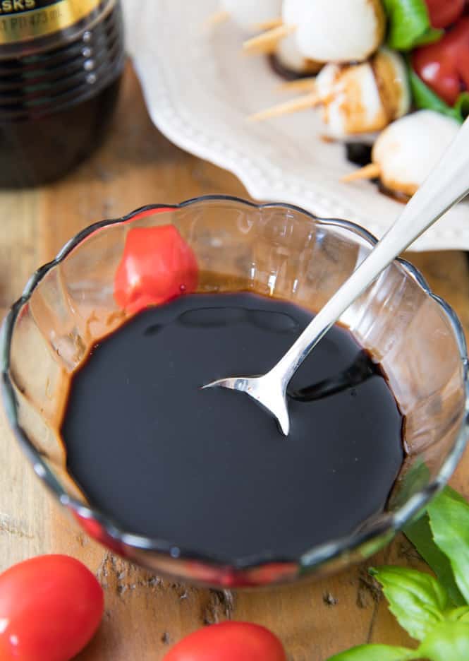 Balsamic vinegar in a clear bowl and metal spoon. 