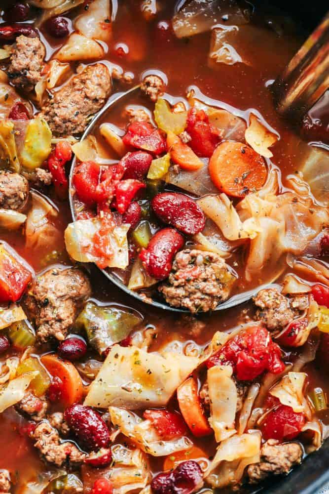 Closeup of beef and cabbage soup with a ladle.