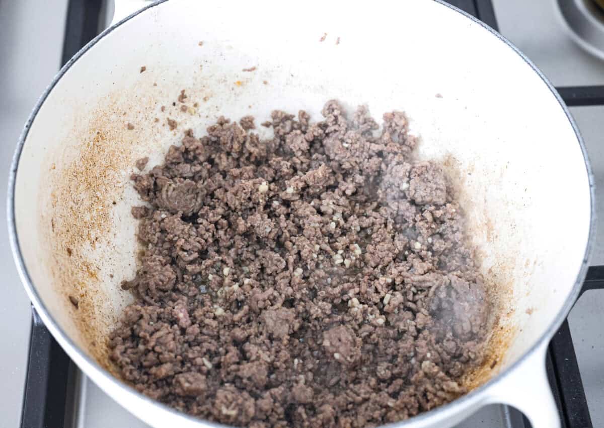 Overhead shot of beef and garlic cooking in the bottom of a pot. 