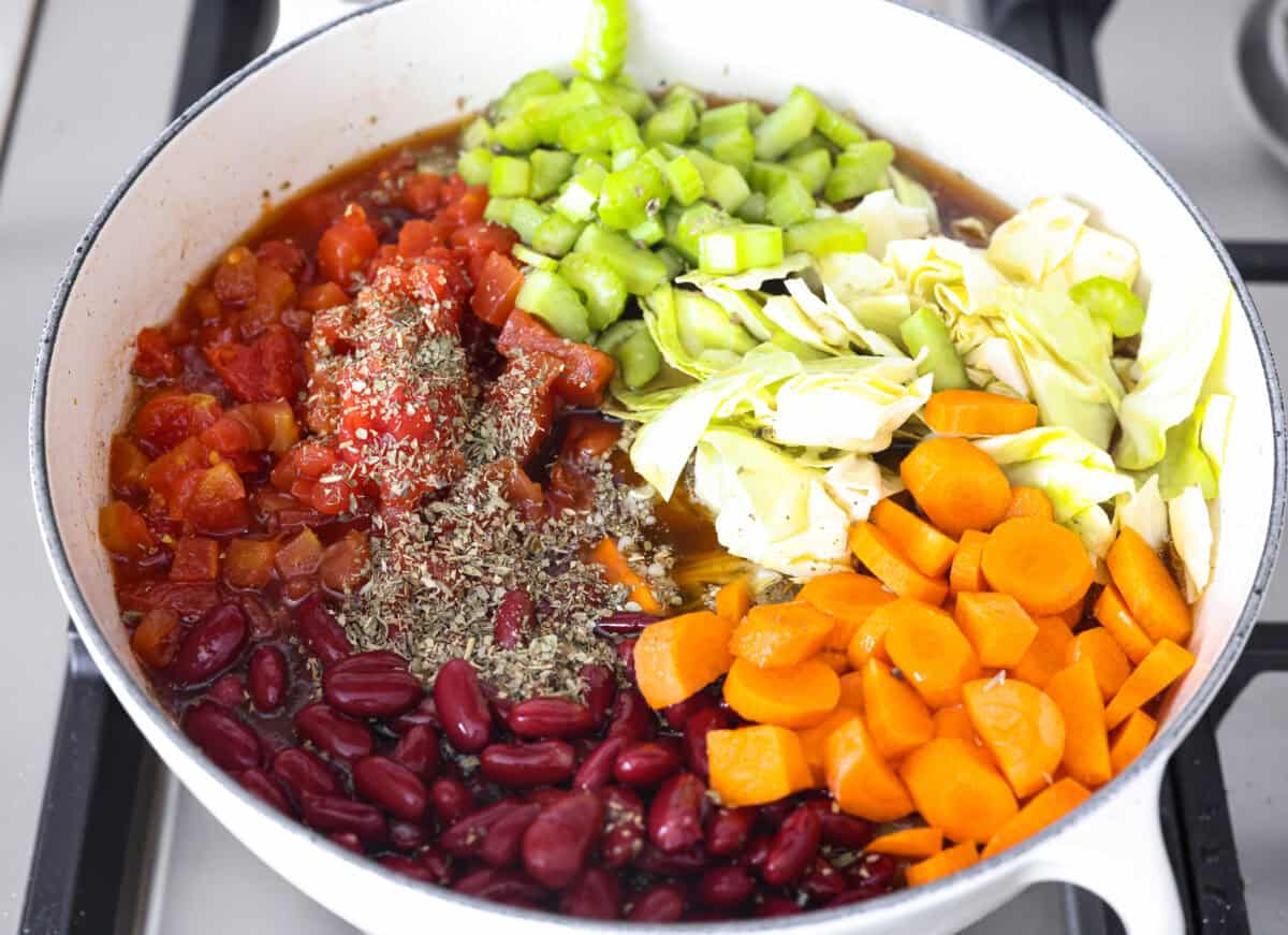 Overhead shot of the vegetables, broth, beans and seasonings added to the pot.