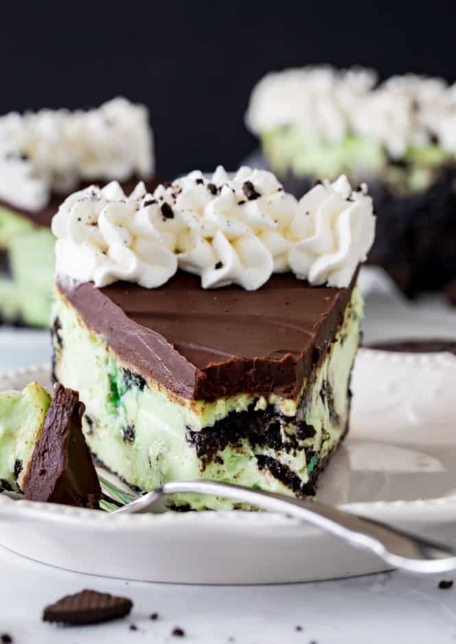 A closeup of Mint Oreo Cheesecake on a white plate with a metal fork. 