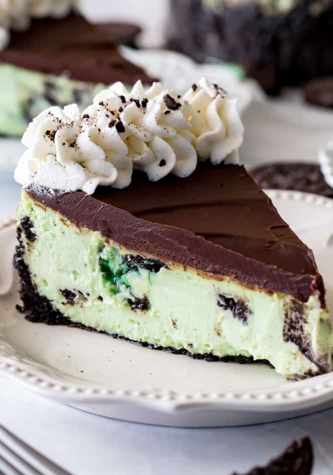 Mint Oreo Cheesecake with whipped topping on a white plate. 