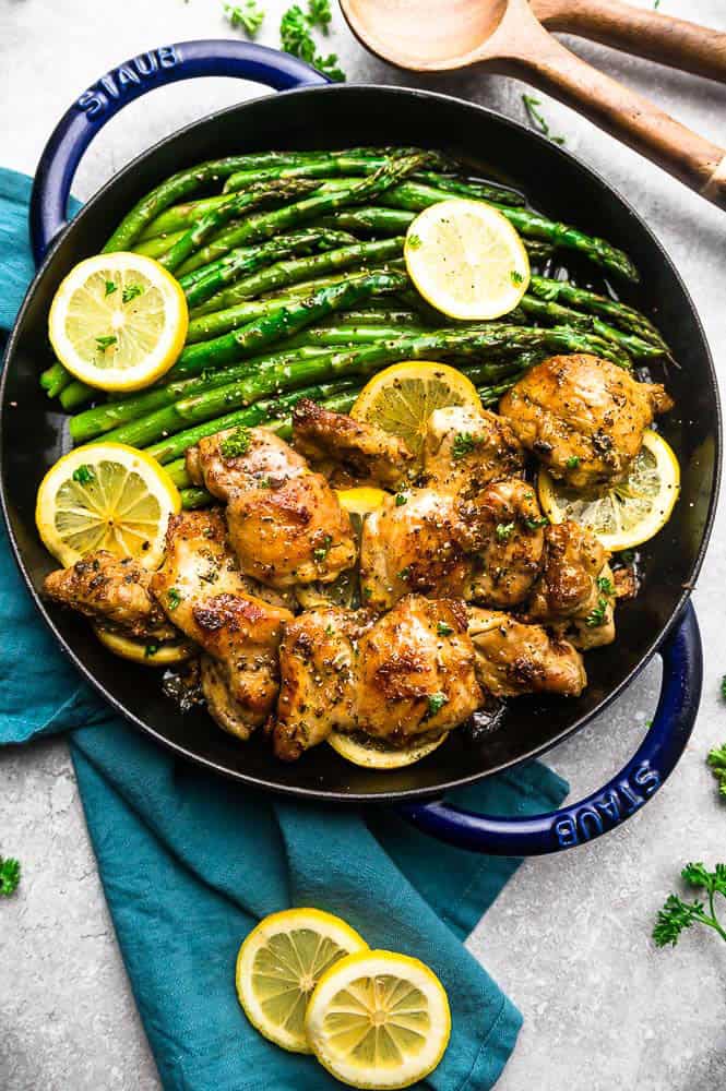 Limón Ajo Pollo en una olla Staub con espárragos y rodajas de limón por encima. 