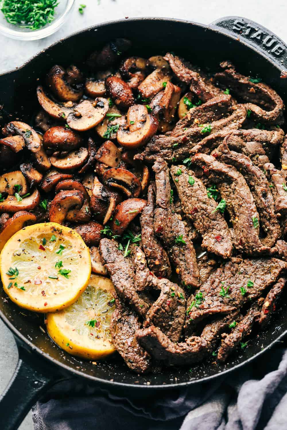 lemon garlic butter flank steak with mushrooms in a Staub skillet