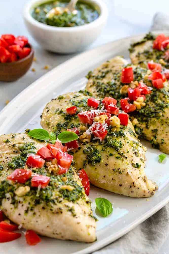 Family-style pesto chicken dinner on a white platter. 