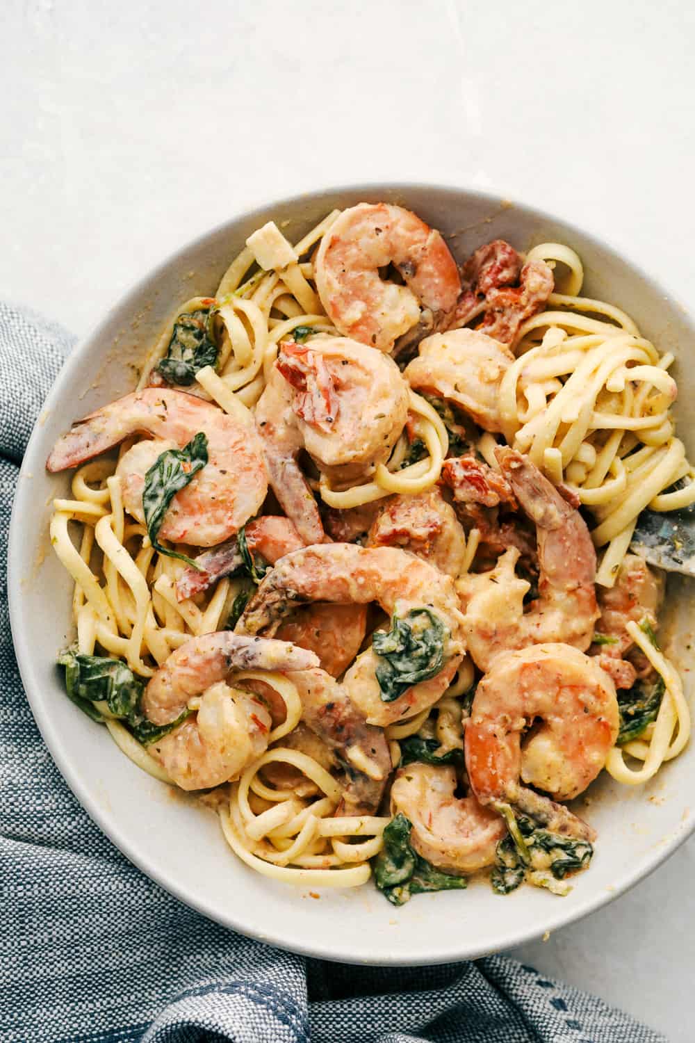 Tuscan shrimp tossed with noodles in a bowl. 