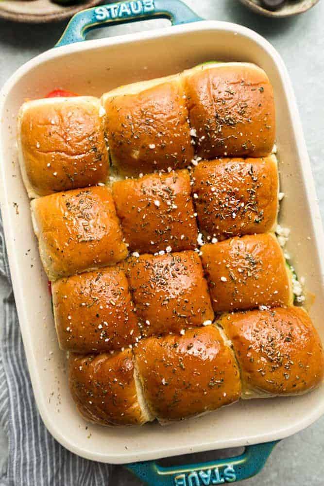 Greek Chicken Sliders in a white iron pan. 