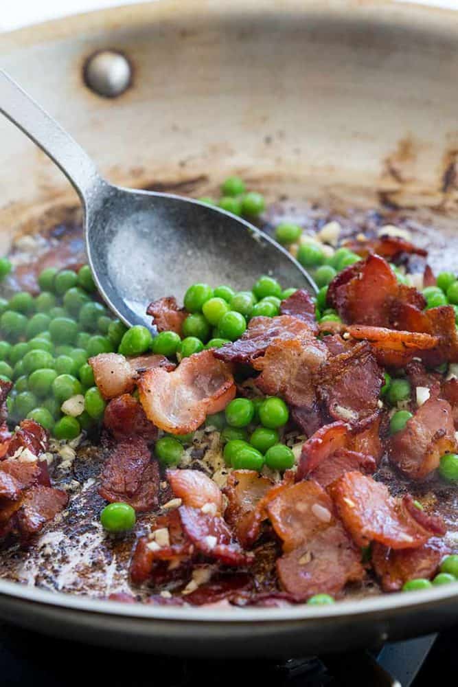 Sautéing peas and sliced bacon in a frying pan.