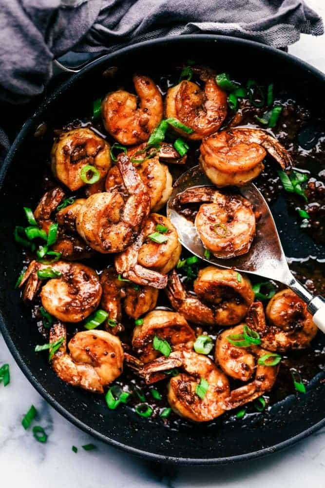 Cajun Garlic Butter Shrimp in a skillet with a metal spoon for serving. 