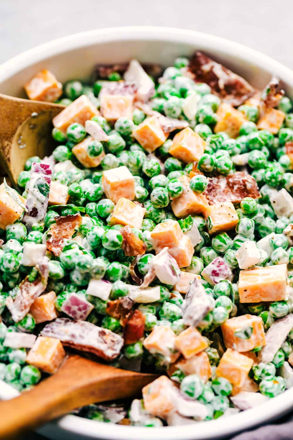 Close up on creamy pea salad with a spoon.