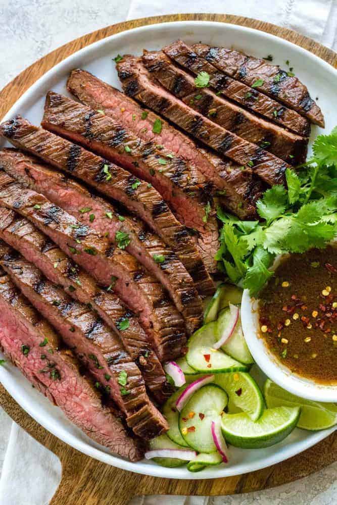 Grilled flank steak with pickled cucumbers on a plate.