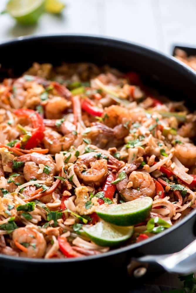 Shrimp Pad Thai in an iron skillet with freshly sliced lime on the side. 