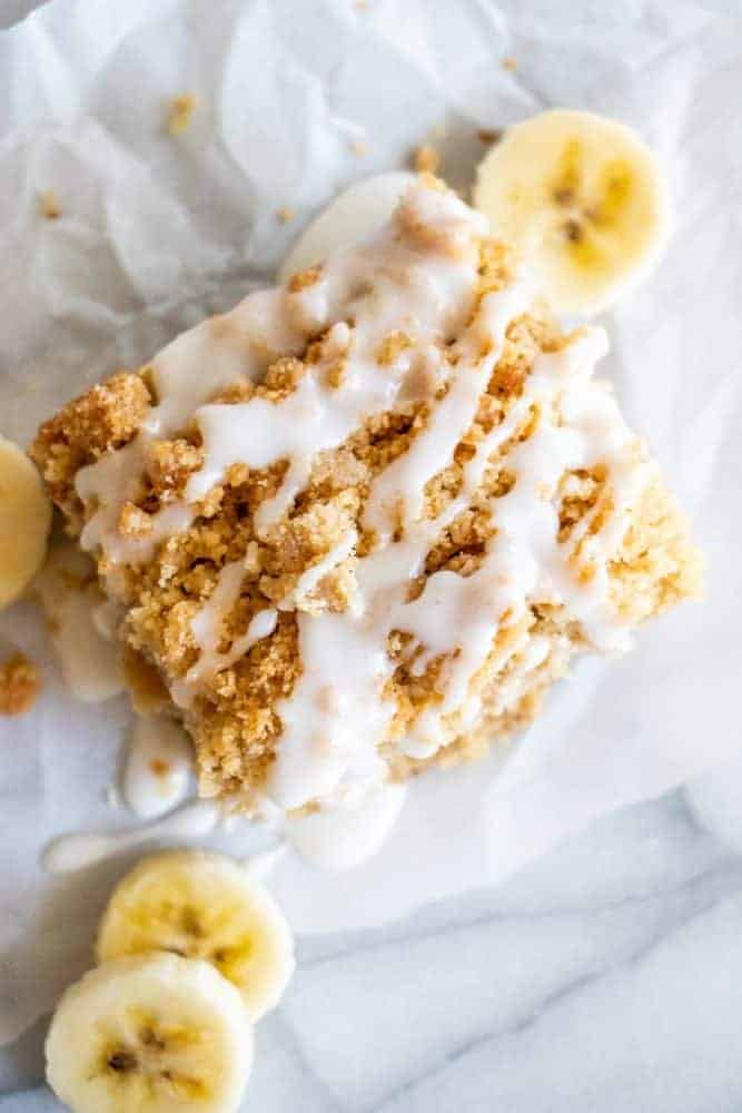 A slice of Banana Bread Crumb Cake with fresh sliced bananas on the side. 