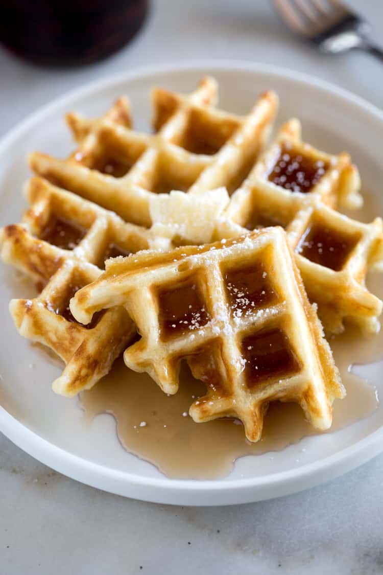 Belgian Waffles topped with syrup, and powdered sugar.