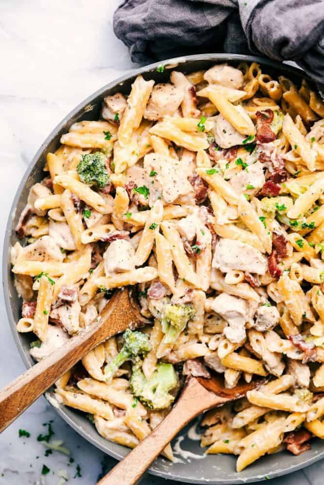 Large bowl of Cheesy Chicken, Bacon and Broccoli Ranch Pasta with two wooden spoons for serving. 