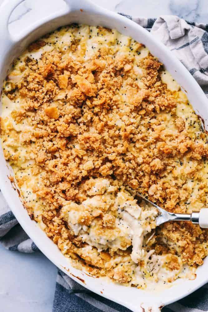 Poppyseed Chicken Casserole in a white platter with a metal spoon. 