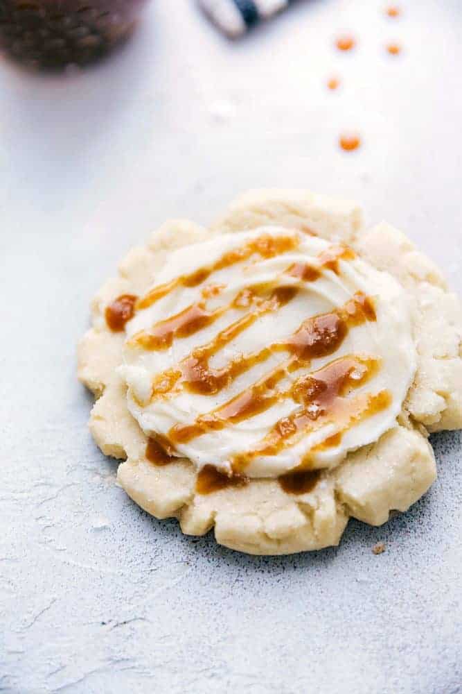 Close up of a sugar cookie with cream cheese frosting and salted caramel drizzle. 