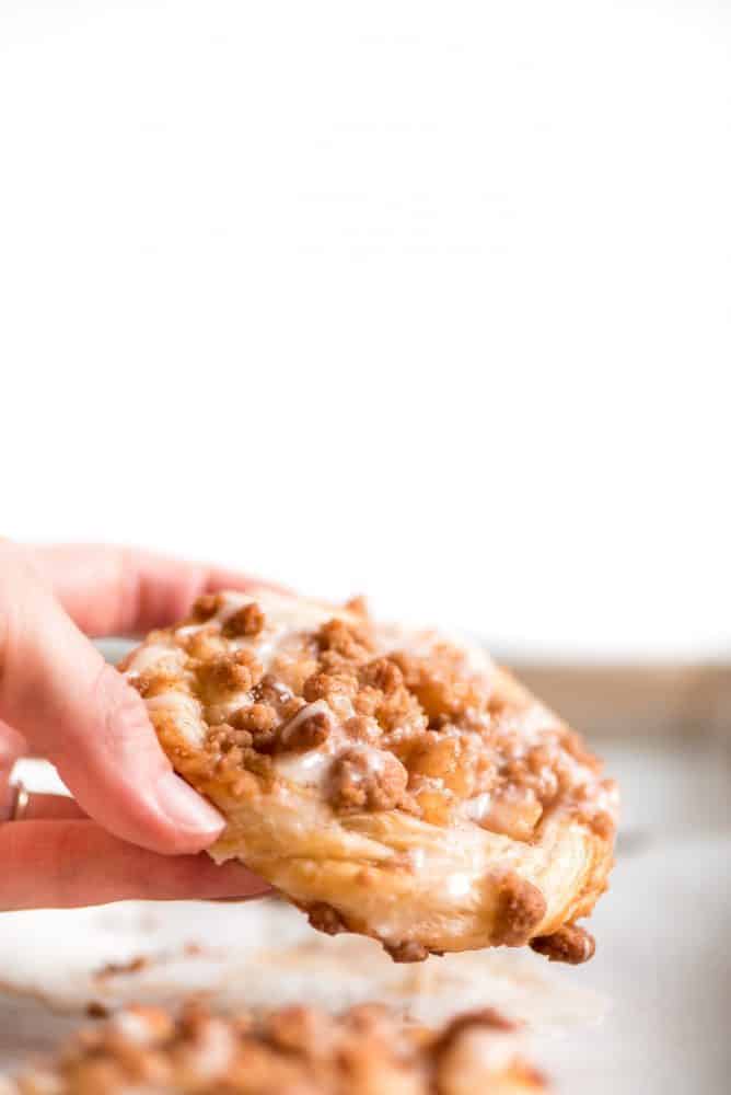 Apple Danish fresh out of the oven being held. 