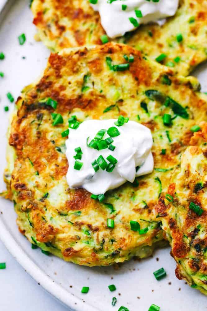 Close up of Cheesy Zucchini Fritters on a white plate. 