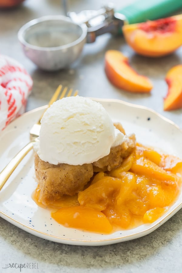 Crock pot peach cobbler with ice cream on a white plate. 